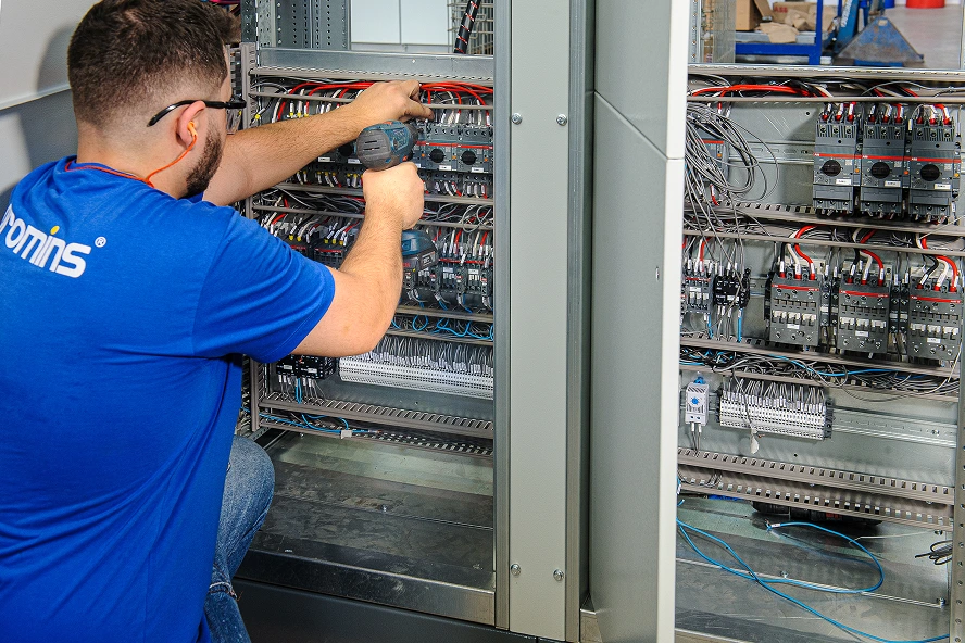 Profissional da Promins realizando serviço de engenharia em painel elétrico